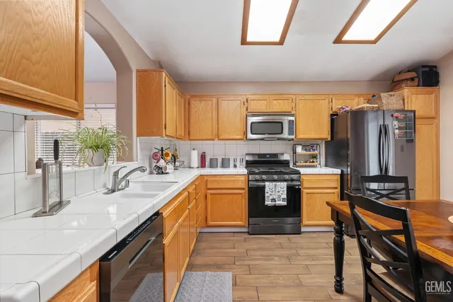 a kitchen with stainless steel appliances granite countertop a refrigerator a stove and a sink
