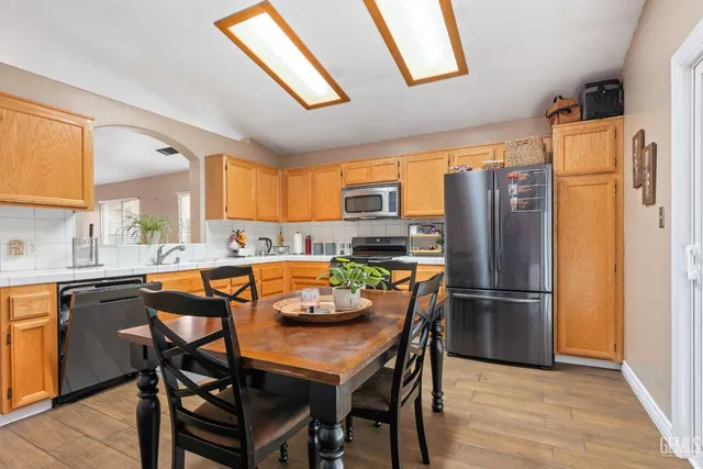a kitchen with stainless steel appliances granite countertop a refrigerator a sink a stove a dining table and chairs