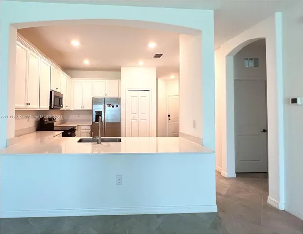 a large kitchen with stainless steel appliances a large counter top a stove and a refrigerator