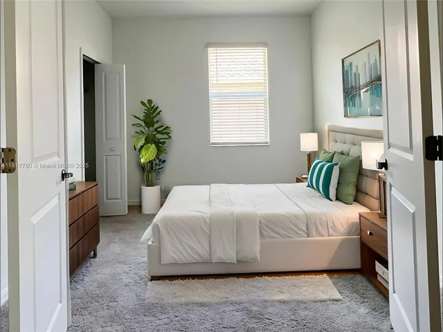 a bedroom with a bed table flowerpot and window