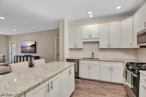 a kitchen with stainless steel appliances granite countertop a sink stove and cabinets