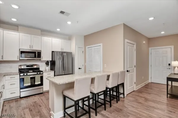 a large kitchen with stainless steel appliances kitchen island granite countertop a table chairs sink and cabinets