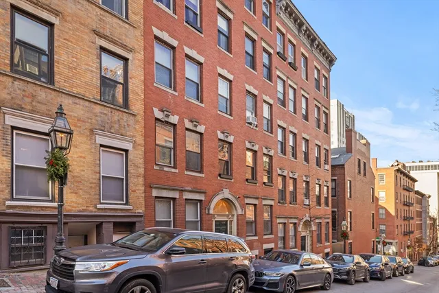 a front view of a building with lot of cars parked