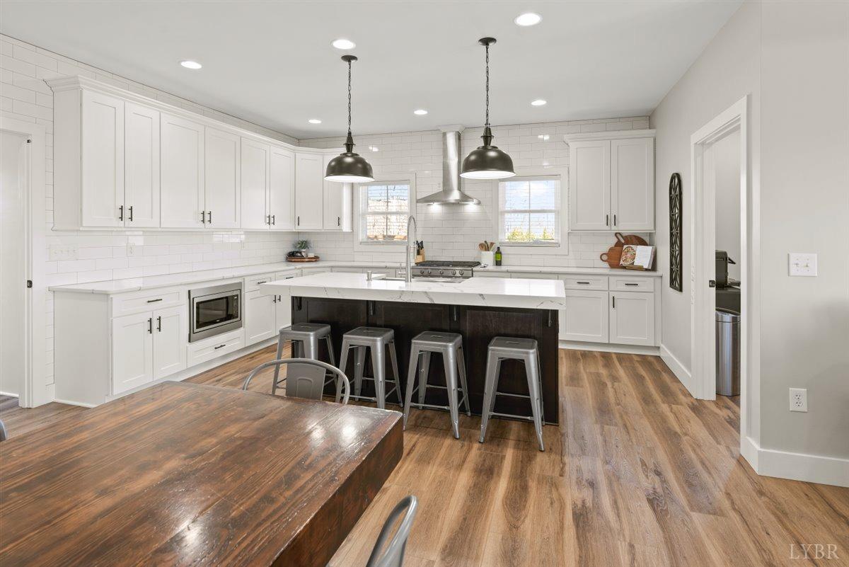 4639 Lowry Road Goode, VA 24556 - Photo 5 of 76 a kitchen with stainless steel appliances granite countertop a kitchen island hardwood floor sink stove and white cabinets