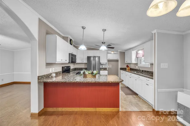 a kitchen with kitchen island granite countertop a sink cabinets and stainless steel appliances