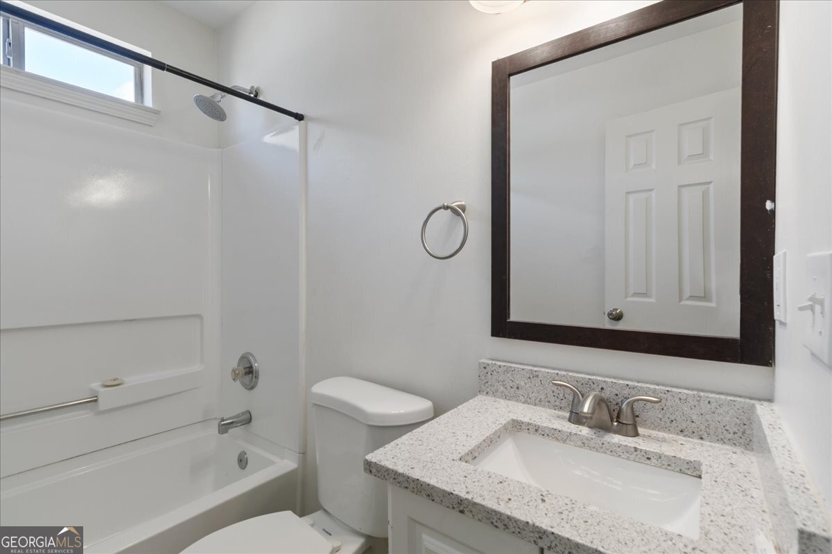 7132 New Dale Road Rex, GA 30273 - Photo 25 of 31 a bathroom with a granite countertop sink a mirror and a toilet