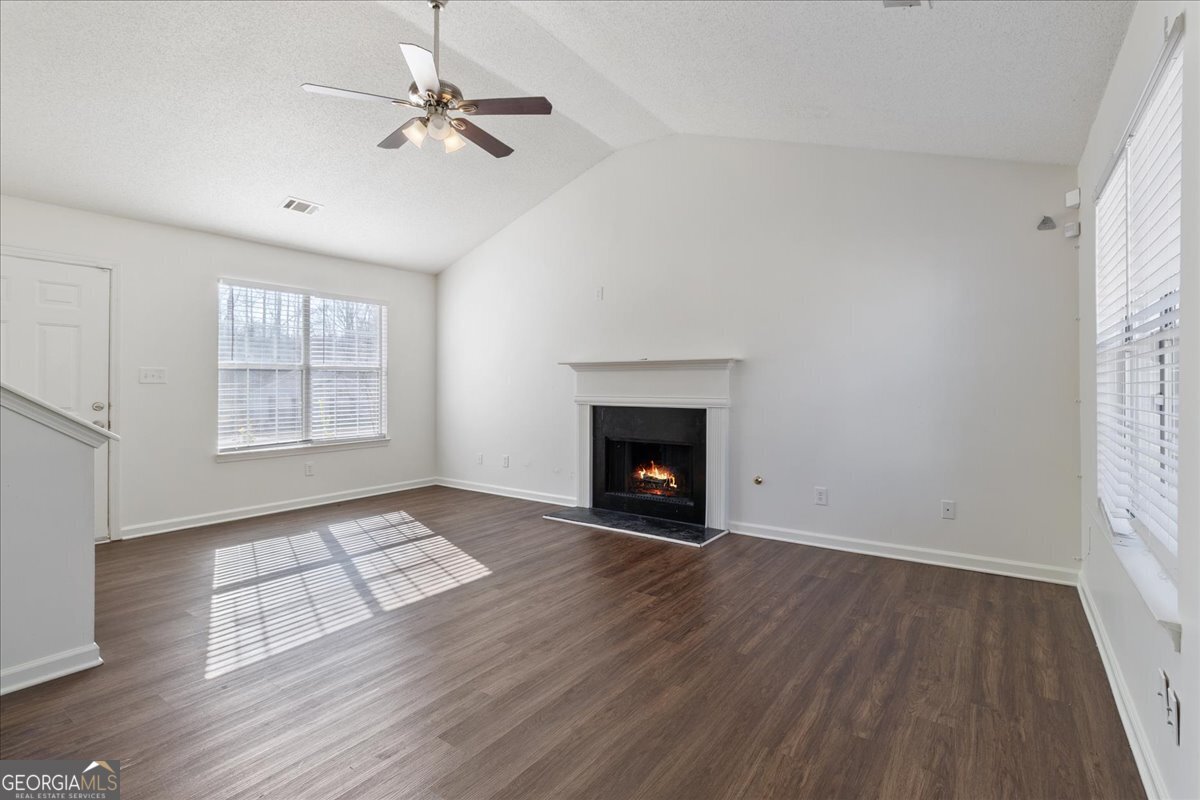 7132 New Dale Road Rex, GA 30273 - Photo 6 of 31 an empty room with windows a fireplace a ceiling fan and wooden floor