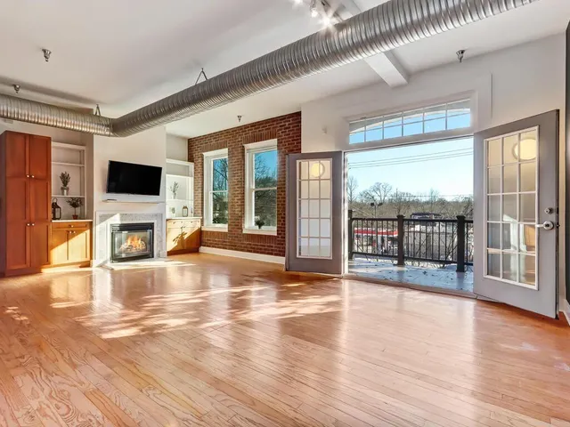 an empty room with wooden floor and large windows