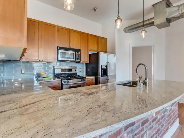 a kitchen with stainless steel appliances granite countertop a stove a sink and a microwave