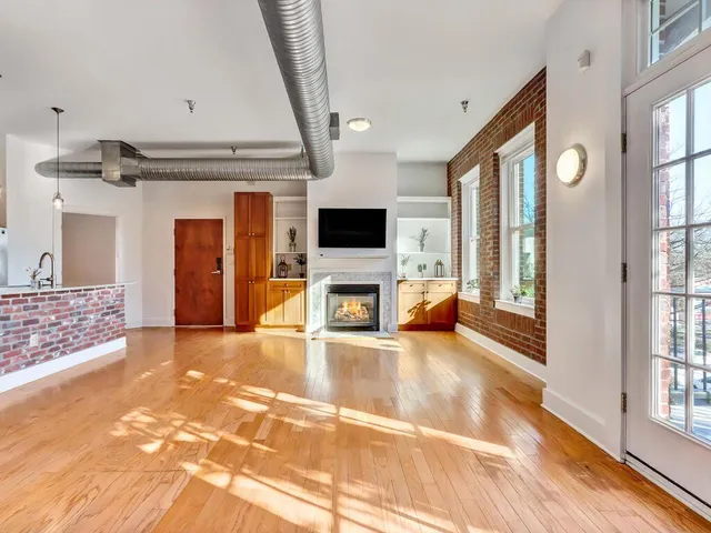 a view of a livingroom with a fireplace a rug wooden floor and a fireplace