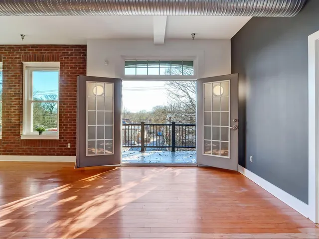 an empty room with wooden floor and windows