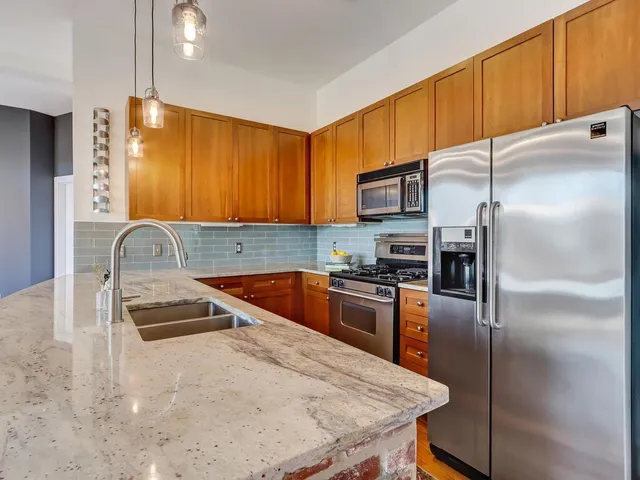 a kitchen with granite countertop a refrigerator a stove a sink a oven with wooden cabinets