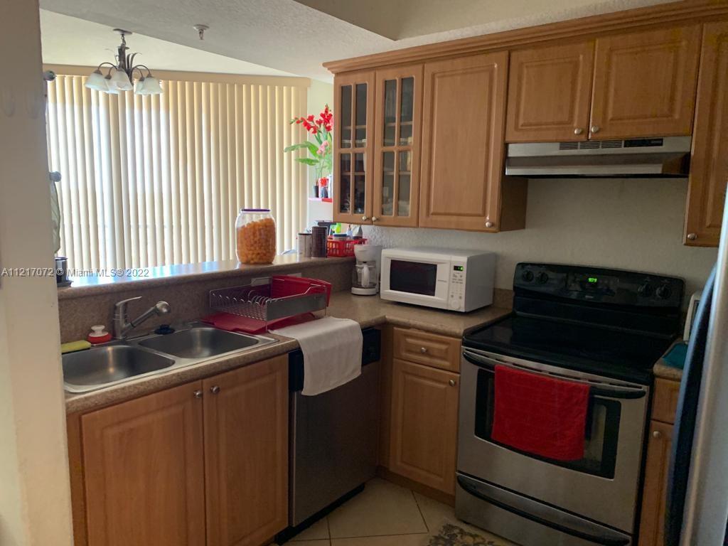 2301 Southwest 27th Avenue, Unit 1200 Miami, FL 33145 - Photo 9 of 9 a kitchen with granite countertop a stove sink and cabinets