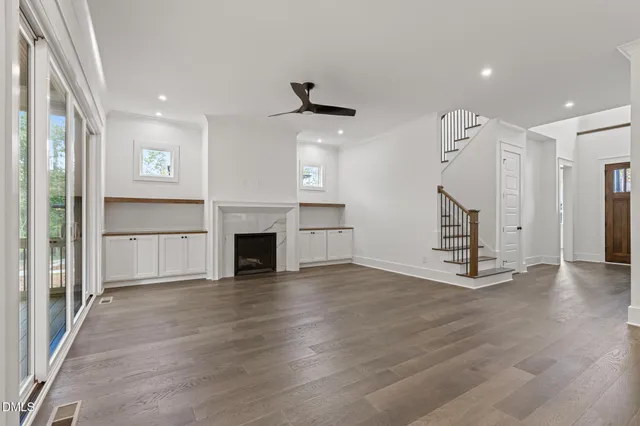 an empty room with wooden floor fireplace and windows