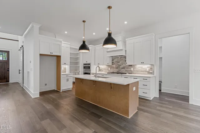 a view of kitchen with granite countertop a sink appliances wooden floor and cabinets