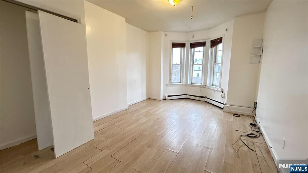 239 South 8th Street, Unit 3 Newark, NJ 07103 - Photo 4 of 7 an empty room with wooden floor and windows