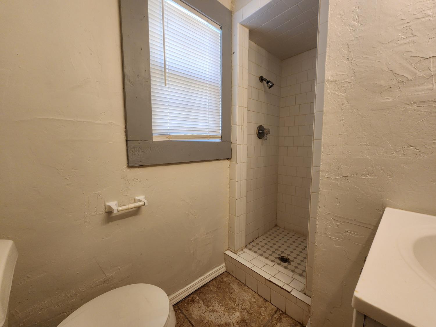 2103 38th Street, Unit B Lubbock, TX 79412 - Photo 5 of 6 a bathroom with a toilet a sink and shower