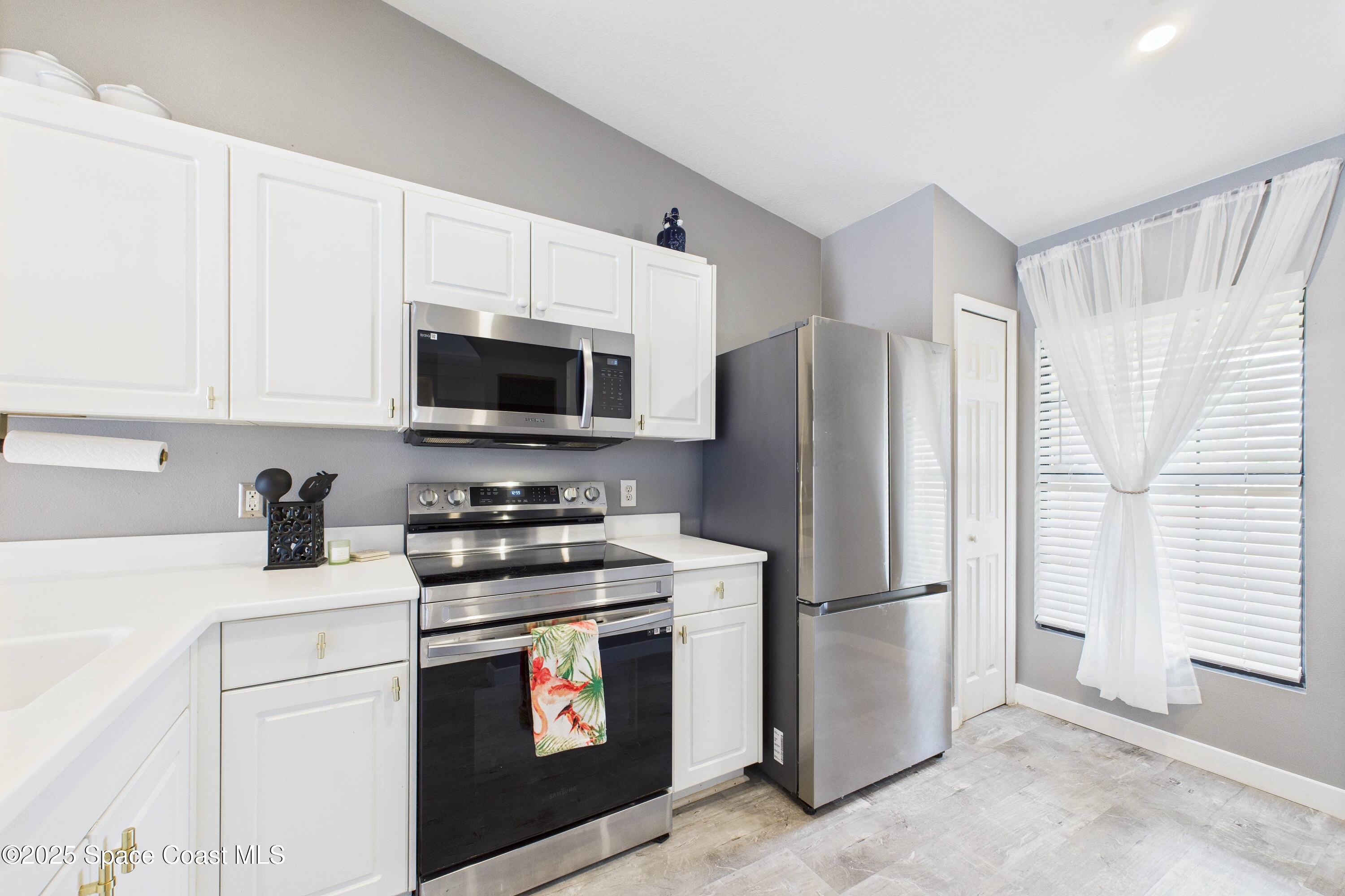 1010 Luminary Circle, Unit 104 Melbourne, FL 32901 - Photo 12 of 42 a kitchen with stainless steel appliances a refrigerator stove and microwave