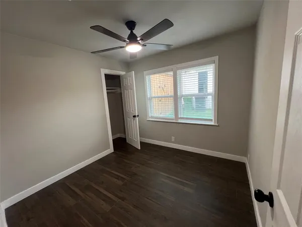 an empty room with wooden floor fan and windows