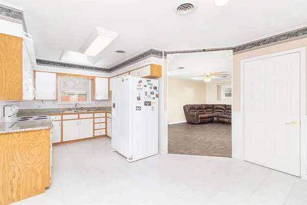 a large white kitchen with a refrigerator a stove a microwave and a dining table with wooden floor