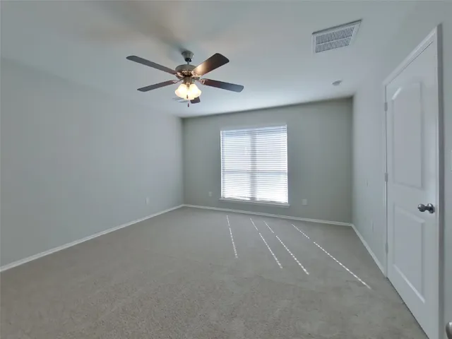 an empty room with windows and ceiling fan