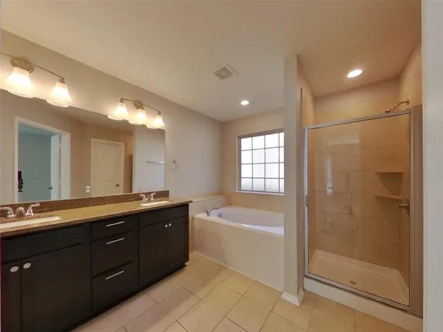 a spacious bathroom with a tub sink shower and mirror