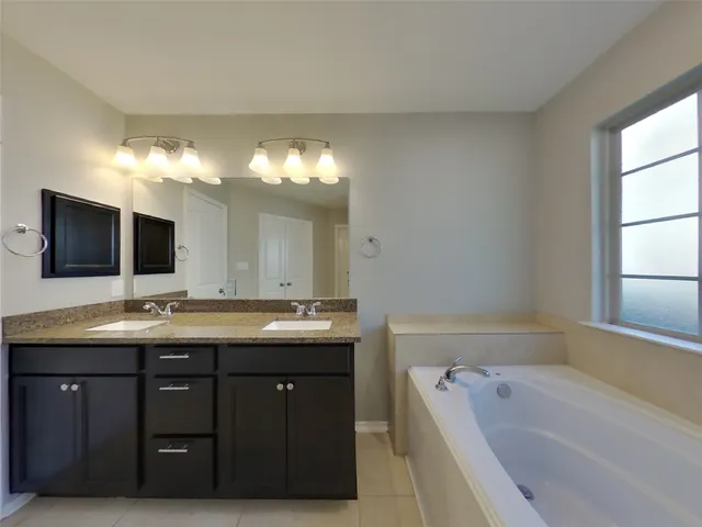 a bathroom with a tub sink and mirror