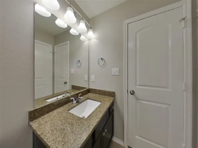 a bathroom with a granite countertop sink and a mirror