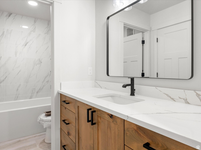 1159 North Broad Hollow Road Garden City, UT 84028 - Photo 32 of 55 Bathroom featuring a wood-finish vanity with black hardware, a white countertop with integrated sink, and a rectangular black-framed mirror