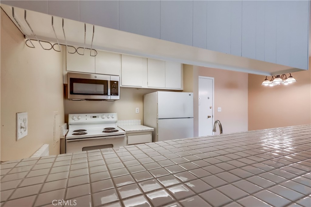 5585 Pacific Coast Highway, Unit 140 Long Beach, CA 90804 - Photo 15 of 47 a kitchen with stainless steel appliances a refrigerator and microwave