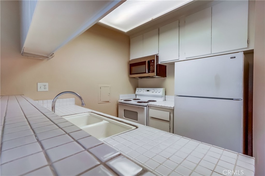 5585 Pacific Coast Highway, Unit 140 Long Beach, CA 90804 - Photo 16 of 47 a kitchen with a refrigerator sink and cabinets