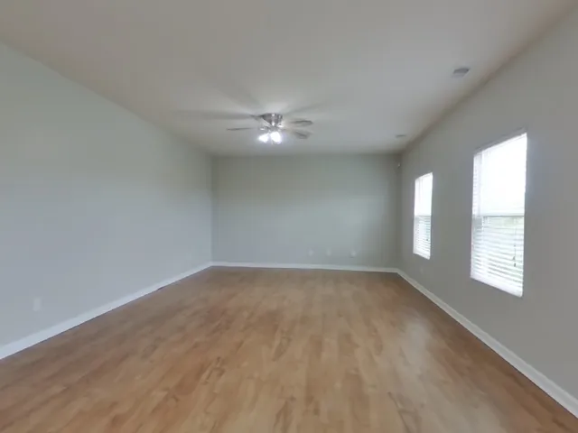 an empty room with windows and fan