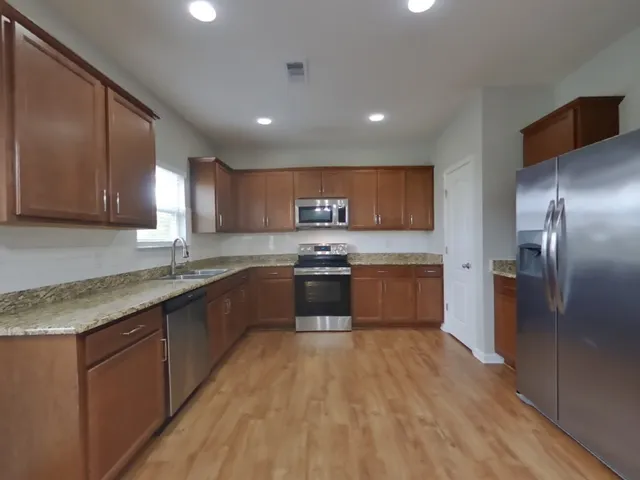 a large kitchen with stainless steel appliances granite countertop a large counter top a sink and a stove