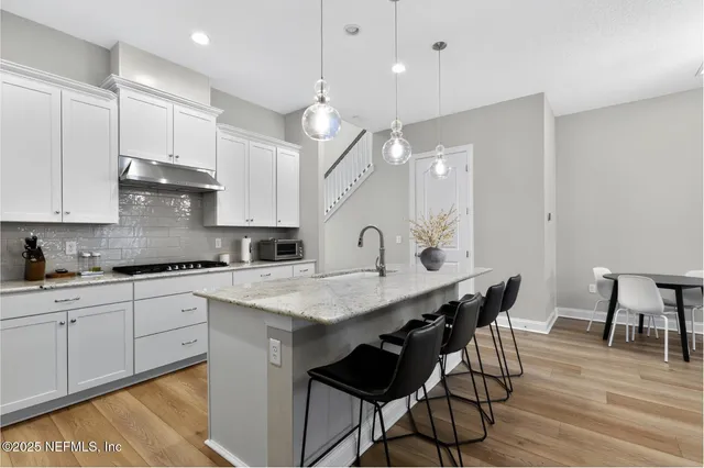 a kitchen with a dining table chairs and white cabinets