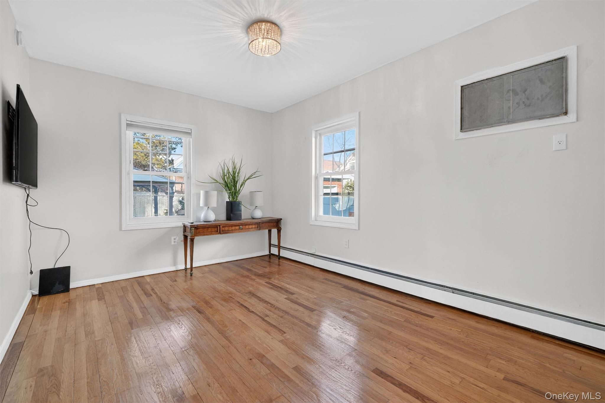 138-16 230th Street Queens, NY 11413 - Photo 17 of 49 First floor bedroom featuring baseboard heating and hardwood / wood-style floors