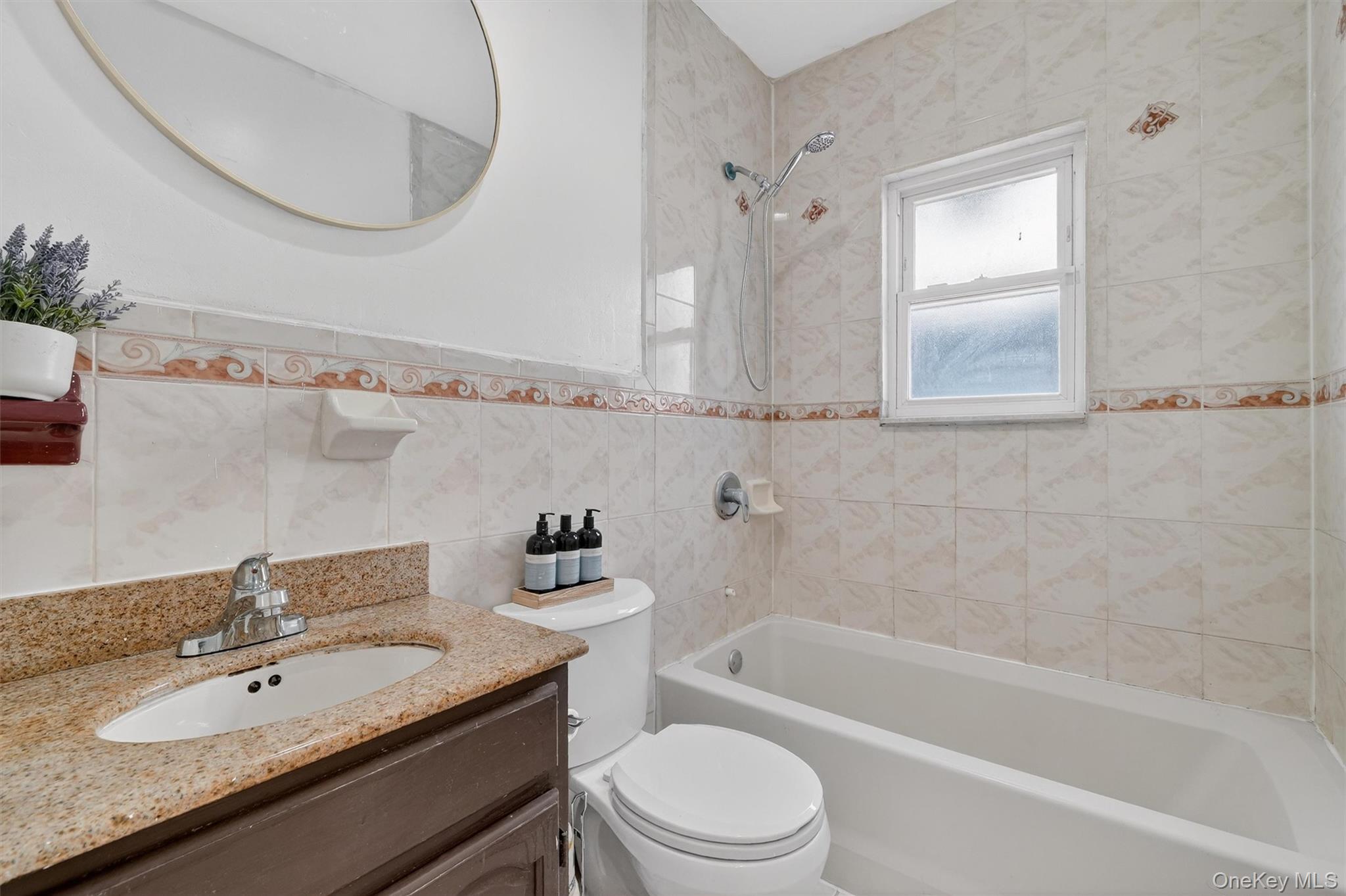 138-16 230th Street Queens, NY 11413 - Photo 18 of 49 Bathroom featuring vanity, shower / bathtub combination, tile walls, and a wainscoted wall