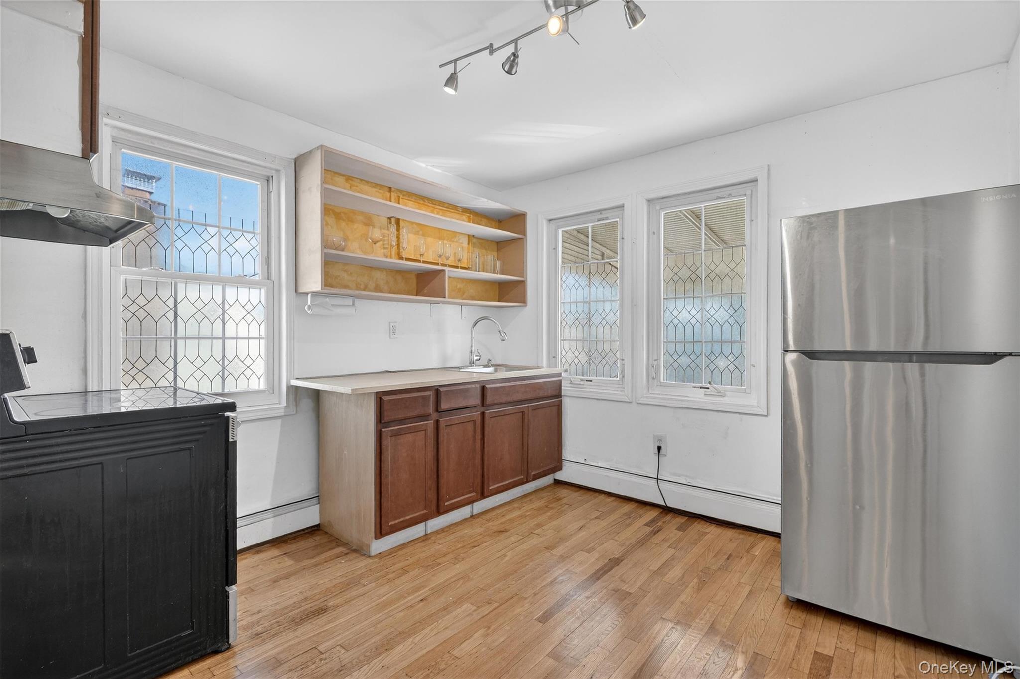 138-16 230th Street Queens, NY 11413 - Photo 20 of 49 2nd floor kitchen featuring freestanding refrigerator, light countertops, brown cabinetry, a baseboard radiator, and light wood-style floors (originally the 2nd bedroom)