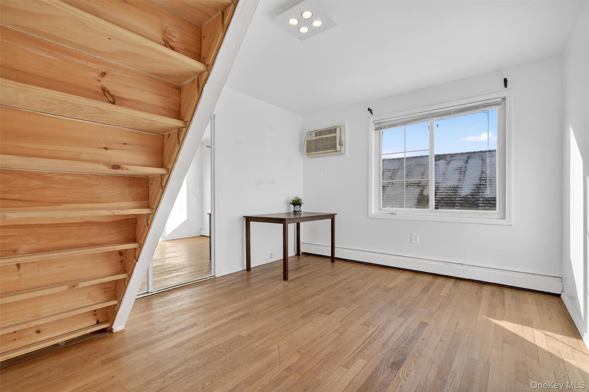 138-16 230th Street Queens, NY 11413 - Photo 28 of 49 4th bedroom with light wood finished floors, baseboard heating, and a wall unit AC