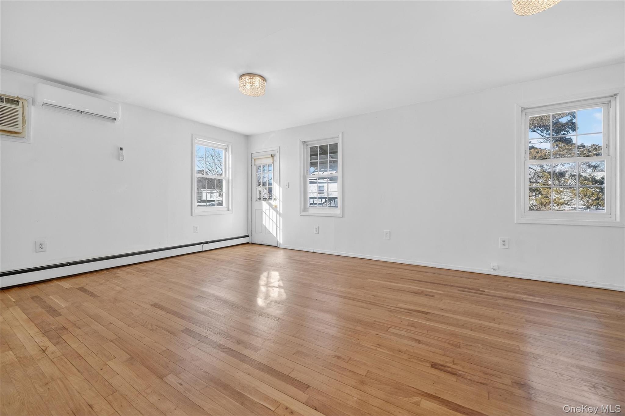 138-16 230th Street Queens, NY 11413 - Photo 31 of 49 5th bedroom featuring light wood-style flooring, a wall mounted air conditioner, a wall mounted AC, and a baseboard radiator