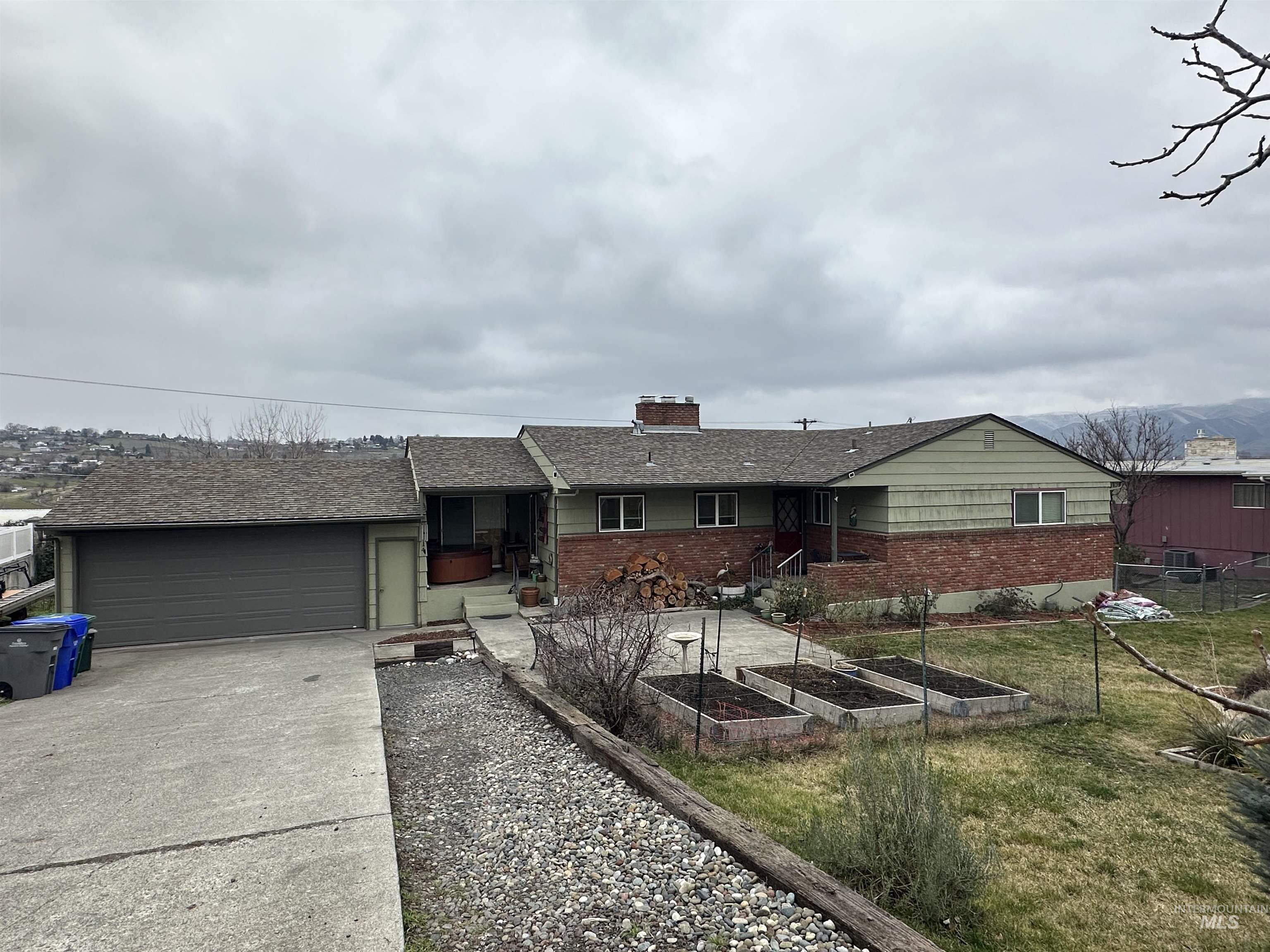 3214 Meadowlark Drive Lewiston, ID 83501 - Photo 1 of 25 Single story home featuring concrete driveway, brick siding, a chimney, and a garden