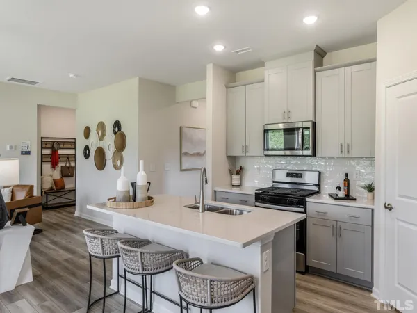 a kitchen with stainless steel appliances a sink a stove a refrigerator cabinets and a dining table