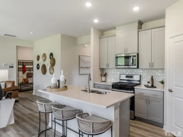 a kitchen with stainless steel appliances a sink a stove a refrigerator cabinets and a dining table