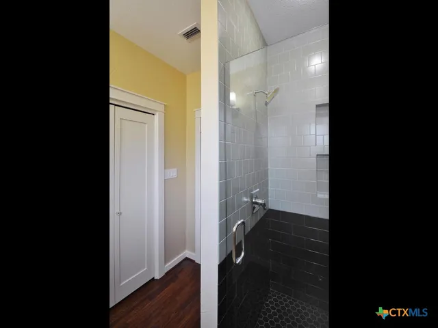 a view of a hallway with wooden floor and a cabinet