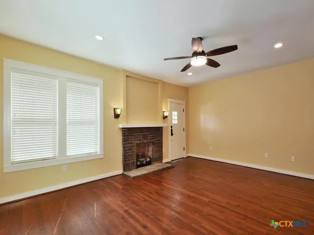 a view of an empty room with a window and wooden floor