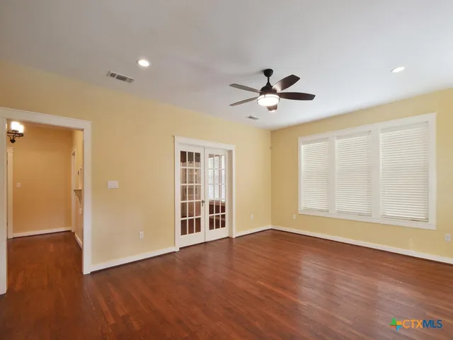 a view of an empty room with wooden floor and a window