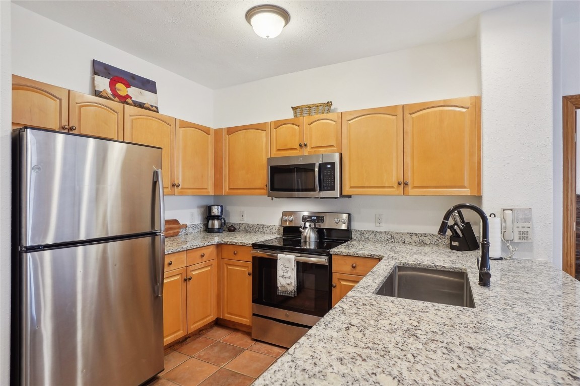 22714 Highway 6, Unit 5941 Keystone, CO 80435 - Photo 5 of 41 a kitchen with stainless steel appliances granite countertop a refrigerator sink stove and microwave