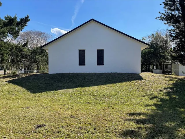 a view of a house with yard and trees in the background
