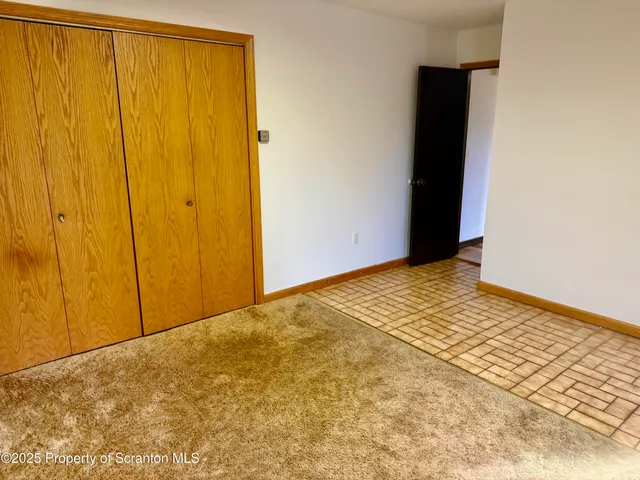 a view of an empty room with wooden floor and a ceiling fan