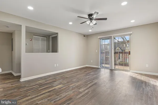 a view of an empty room with a window and wooden floor