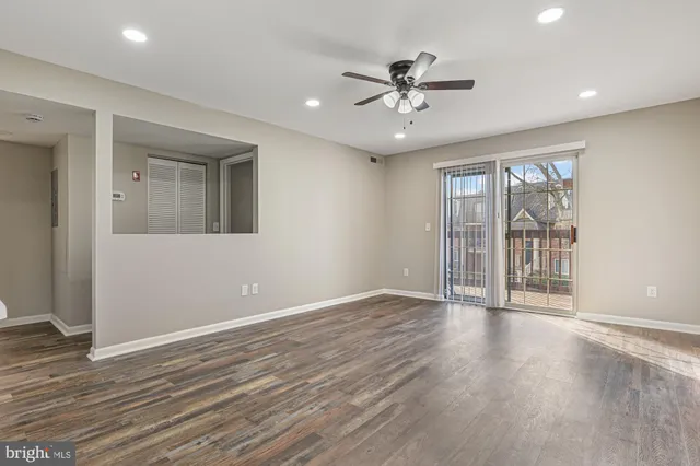 a view of an empty room with a window and wooden floor
